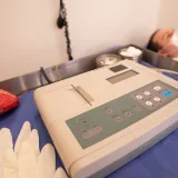 Primer plano de una máquina de ECG y un modelo de corazón en un entorno hospitalario.