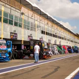 Varios camiones alineados en el pit lane de Londrina durante un evento de automovilismo.