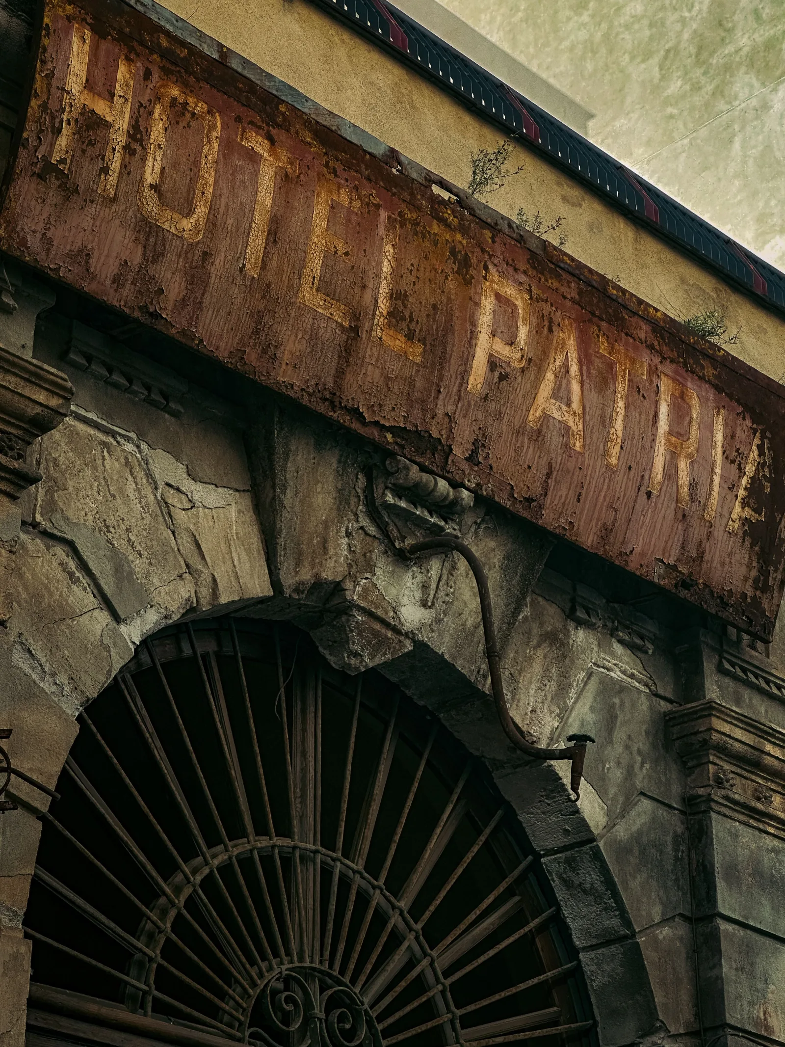 Letrero desgastado del Hotel Patria en un edificio antiguo de Palermo, Sicilia, que evoca el encanto de otra época.