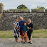 Family posing by a historic fortress wall in Ponte de Lima, Portugal, during a pleasant summer day.