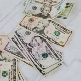 Crisp US dollar bills scattered on a marble surface, symbolizing wealth and finance.