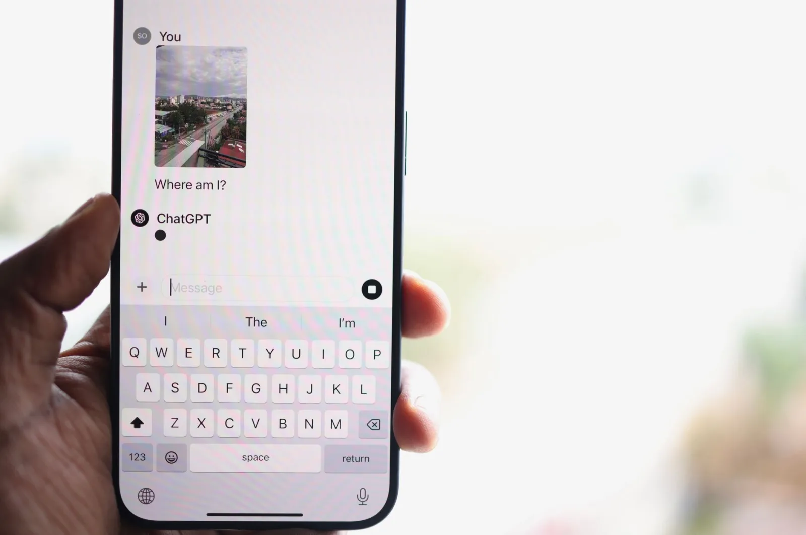 Una persona sostiene un smartphone que muestra un chat con ChatGPT, preguntando sobre su ubicación.