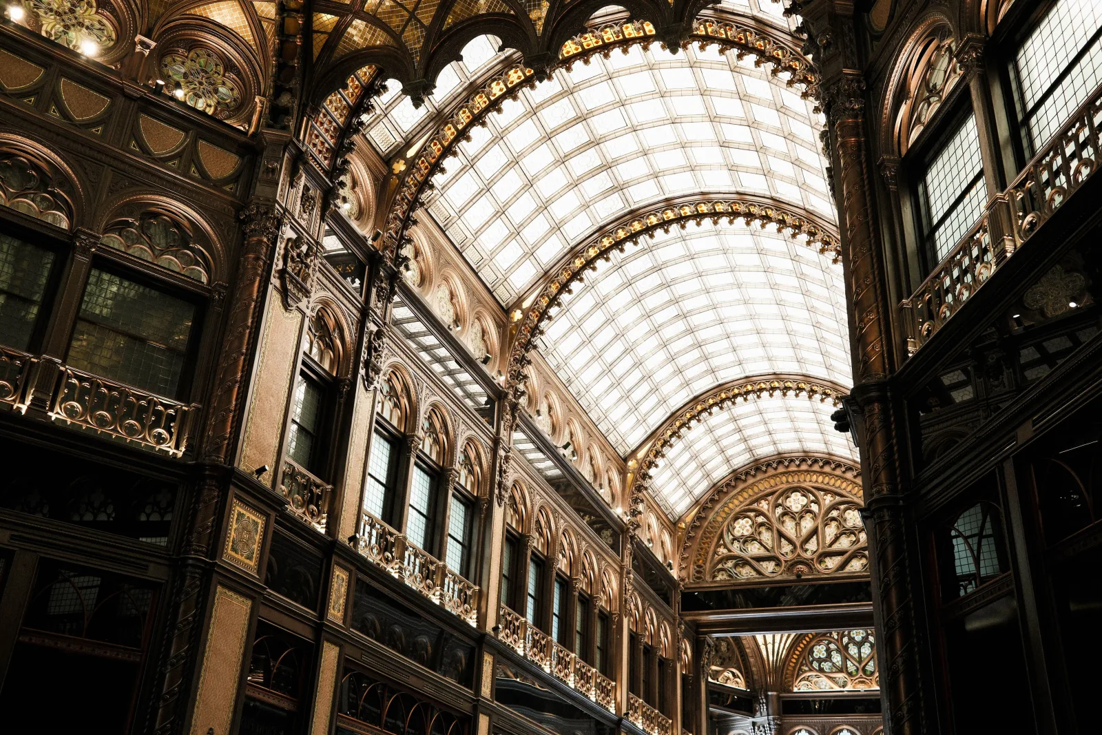 Intrincado interior del histórico Parisi Udvar de Budapest, con un impresionante techo de cristal y detalles ornamentados.
