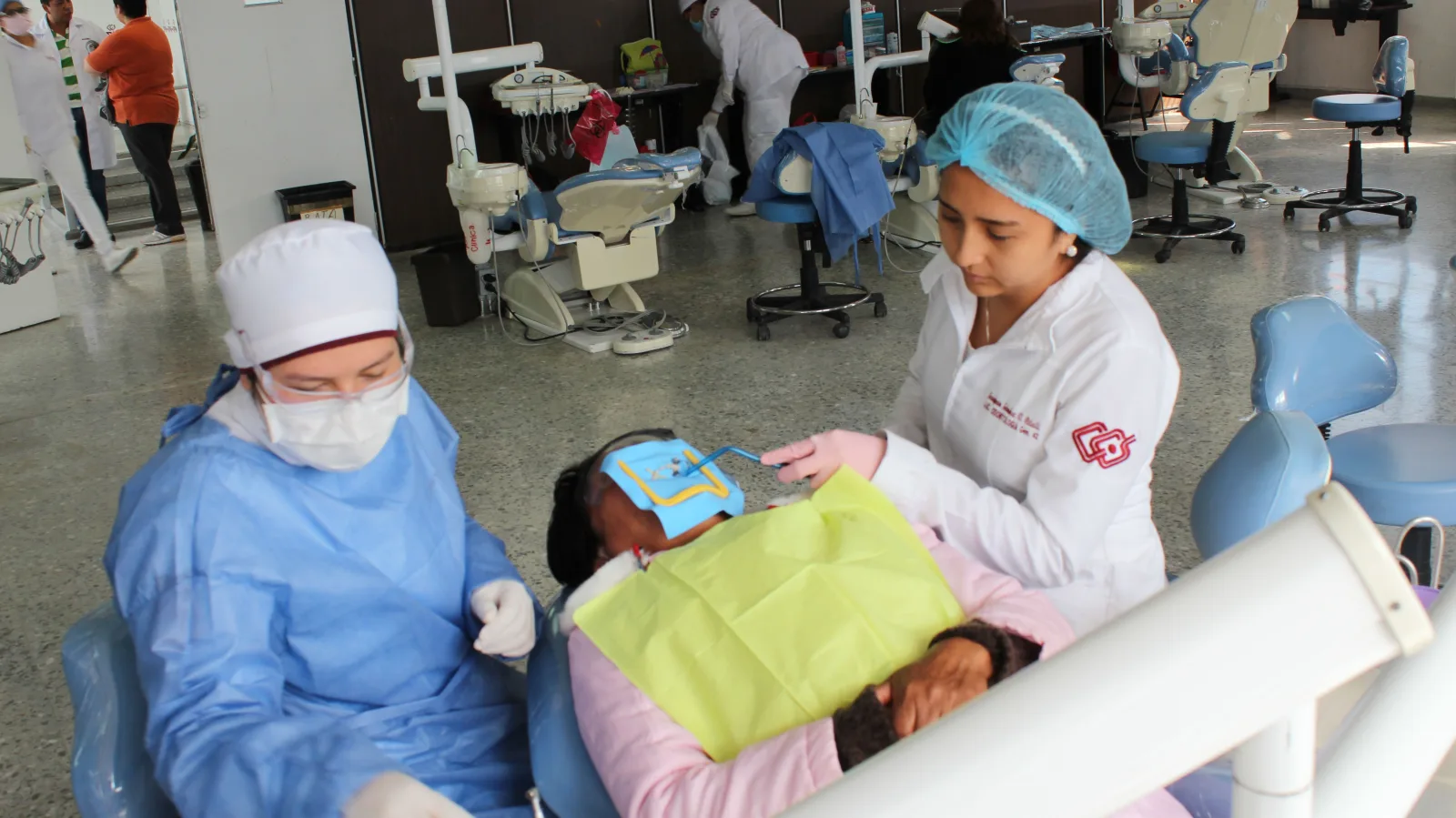 Dentistas trabajando con un paciente durante un procedimiento dental en un entorno de clínica moderna.
