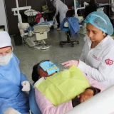 Dentistas trabajando con un paciente durante un procedimiento dental en un entorno de clínica moderna.