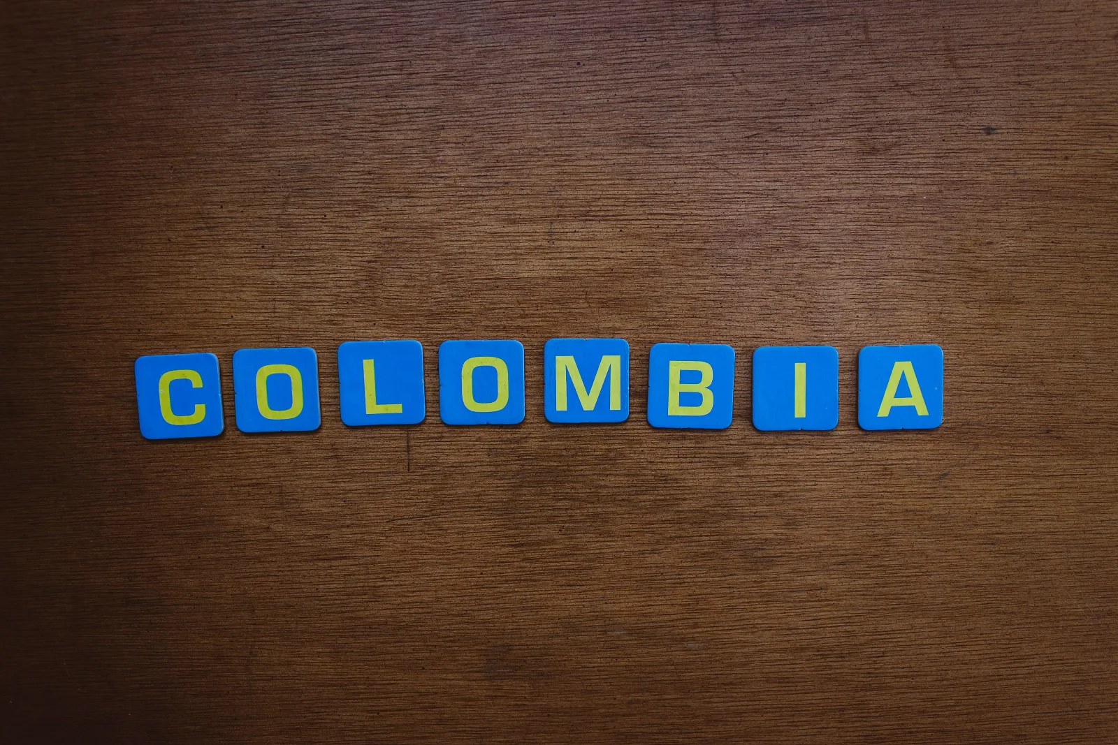 Un primer plano de letras de azulejos coloridos que forman la palabra «Colombia» sobre una superficie de madera.