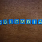 Un primer plano de letras de azulejos coloridos que forman la palabra «Colombia» sobre una superficie de madera.