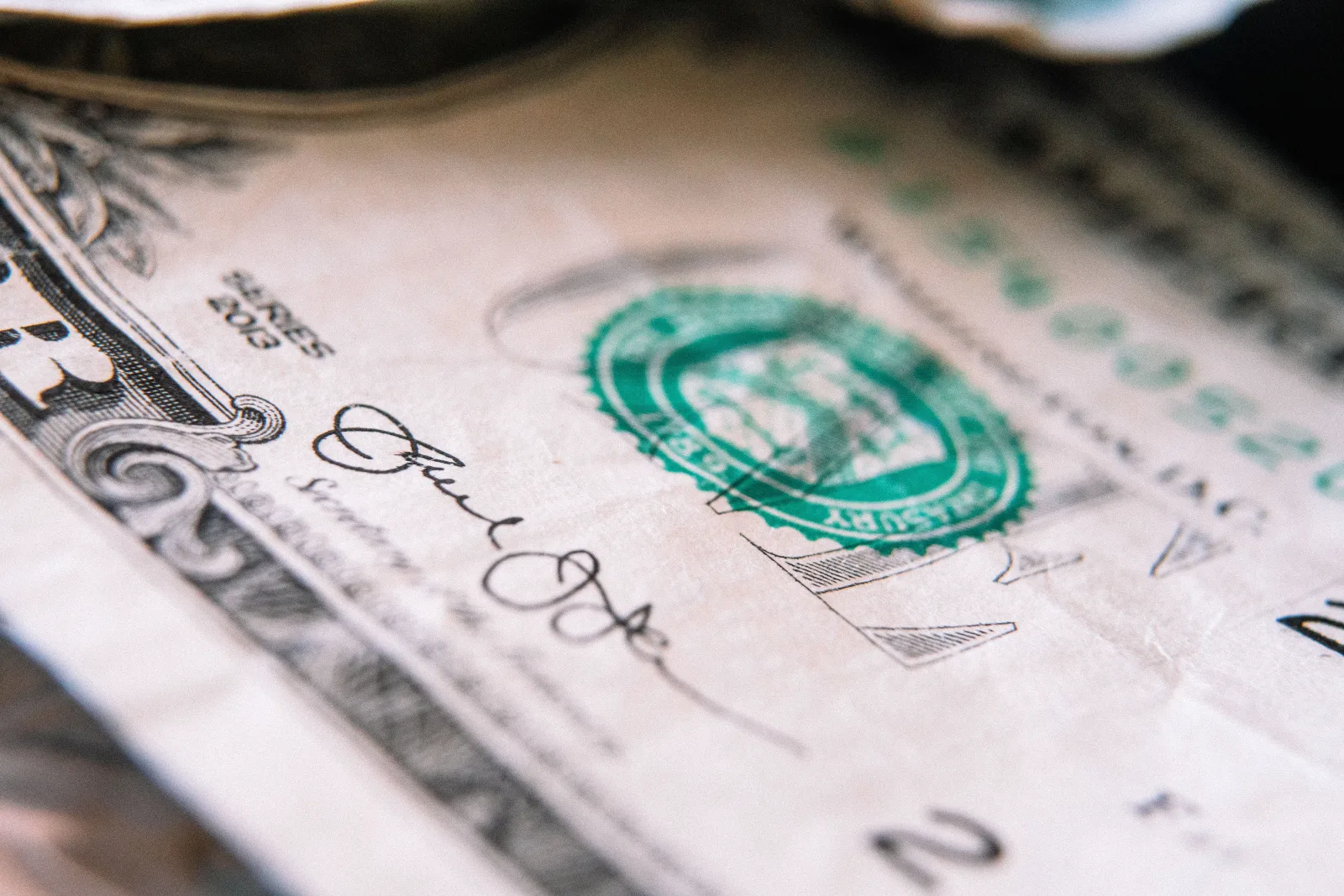 Primer plano desde arriba de un billete de un dólar estadounidense colocado sobre una mesa con el anverso hacia arriba.