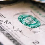 Primer plano desde arriba de un billete de un dólar estadounidense colocado sobre una mesa con el anverso hacia arriba.