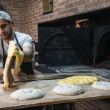A baker skillfully preparing flatbread in a traditional oven, highlighting craftsmanship.