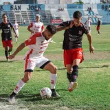 Partido de fútbol competitivo con jugadores en acción en un campo de fútbol al aire libre.