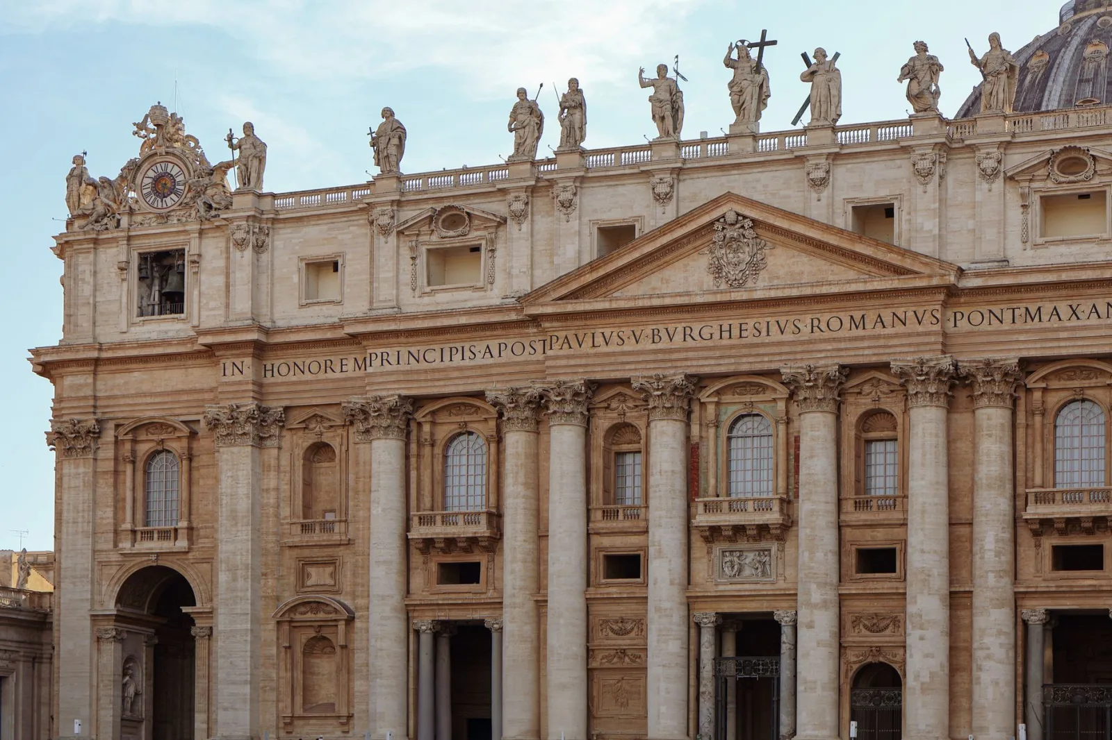 Vista detallada de la fachada de la basílica de San Pedro, con estatuas y columnas, en la Ciudad del Vaticano.