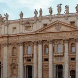 Vista detallada de la fachada de la basílica de San Pedro, con estatuas y columnas, en la Ciudad del Vaticano.