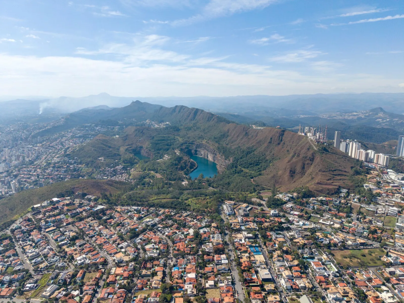Vista aérea panorámica de Belo Horizonte, donde se aprecian la Serra do Curral y el desarrollo urbano que rodea un lago en Minas Gerais, Brasil.