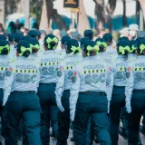 Mujeres policías uniformadas desfilando en un desfile con moños verdes llamativos en la ciudad.