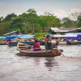 A man and woman navigating a motorboat on the Amazon River near Leticia, Colombia. Vibrant waterway scene.