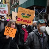 Manifestantes se reúnen en el barrio chino de Nueva York para protestar contra los nuevos planes de construcción de cárceles, sosteniendo carteles y pancartas.