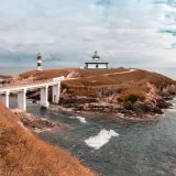 Una vista cautivadora de una isla costera con un faro y un puente bajo un cielo nublado.