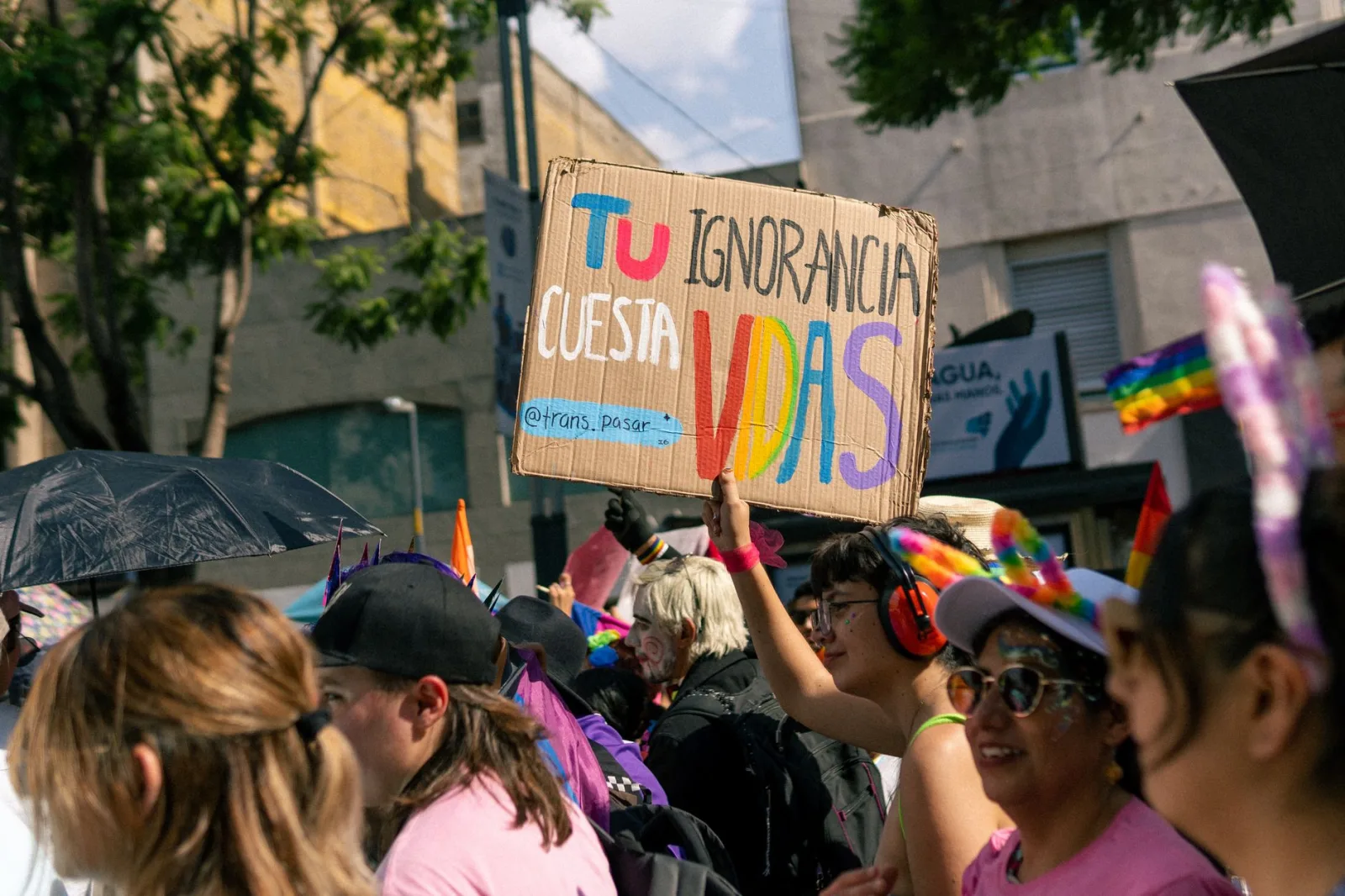 Escena colorida de una marcha del orgullo, con carteles de protesta y participantes diversos que celebran los derechos LGBTQ.