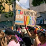 Escena colorida de una marcha del orgullo, con carteles de protesta y participantes diversos que celebran los derechos LGBTQ.