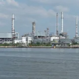 A large oil refinery complex next to the water with cloudy skies.