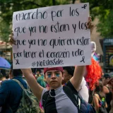 Una vibrante marcha del orgullo LGBTQ con una persona participante que sostiene un emotivo cartel de concienciación.