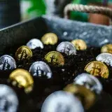 Closeup of bitcoin coins buried in soil, symbolizing digital currency and investment growth.