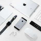 Flat lay of Apple devices including iPhone, iPad, MacBook, and Watch on a white surface, ideal for tech enthusiasts.