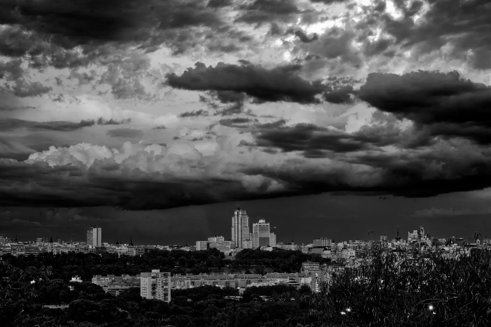 Una cautivadora vista en blanco y negro del perfil urbano de Madrid bajo nubes dramáticas.