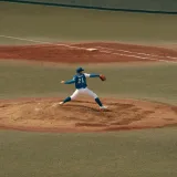 Jugador de béisbol en medio de un lanzamiento durante un partido en un campo de béisbol de Tokio. Capturando la intensidad y la concentración del deporte.