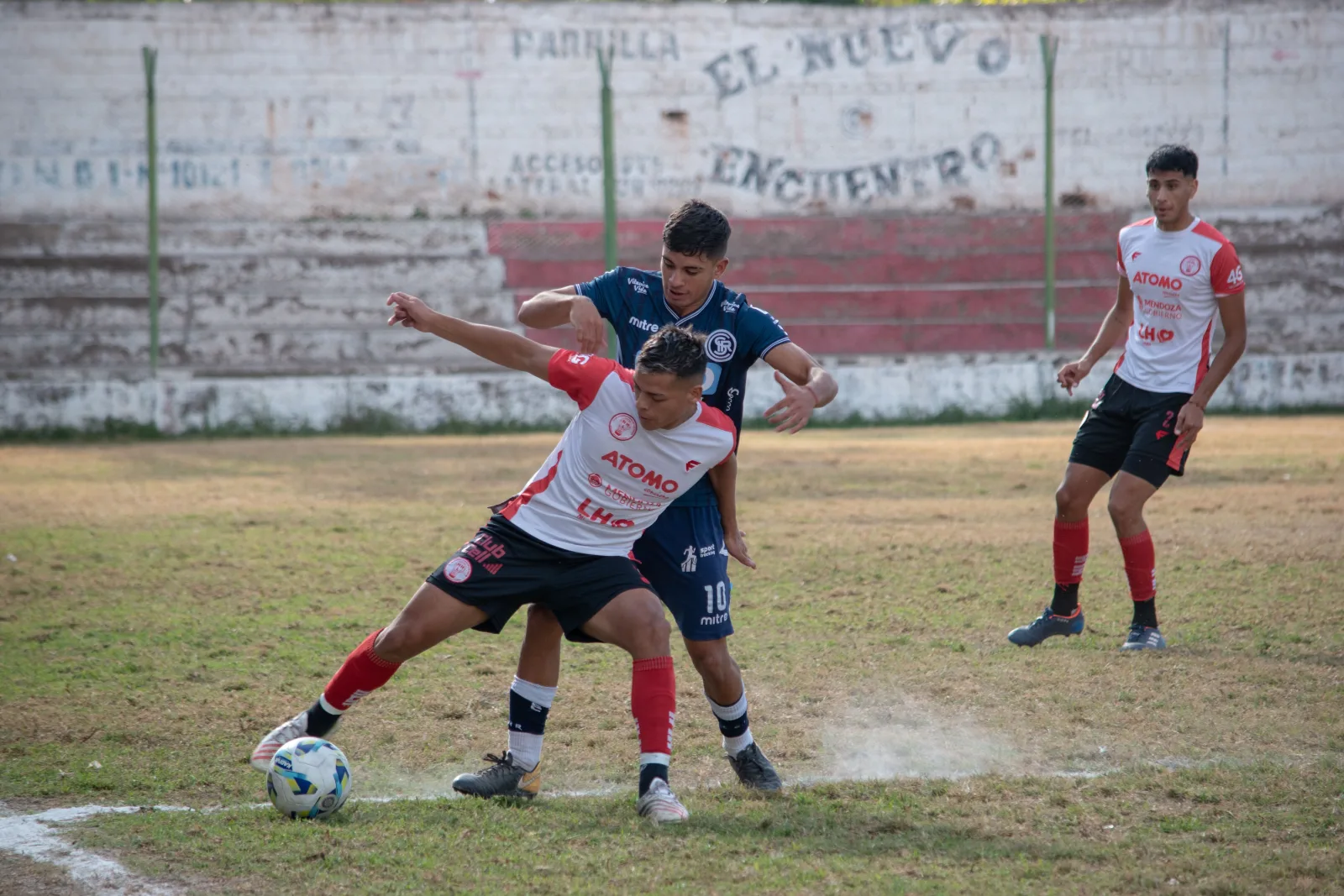 Jóvenes atletas participan en un partido competitivo de fútbol en una cancha de césped, demostrando habilidad y trabajo en equipo.