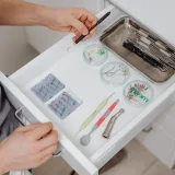 Un dentista organiza instrumentos dentales en un cajón de la clínica, mostrando equipos modernos.