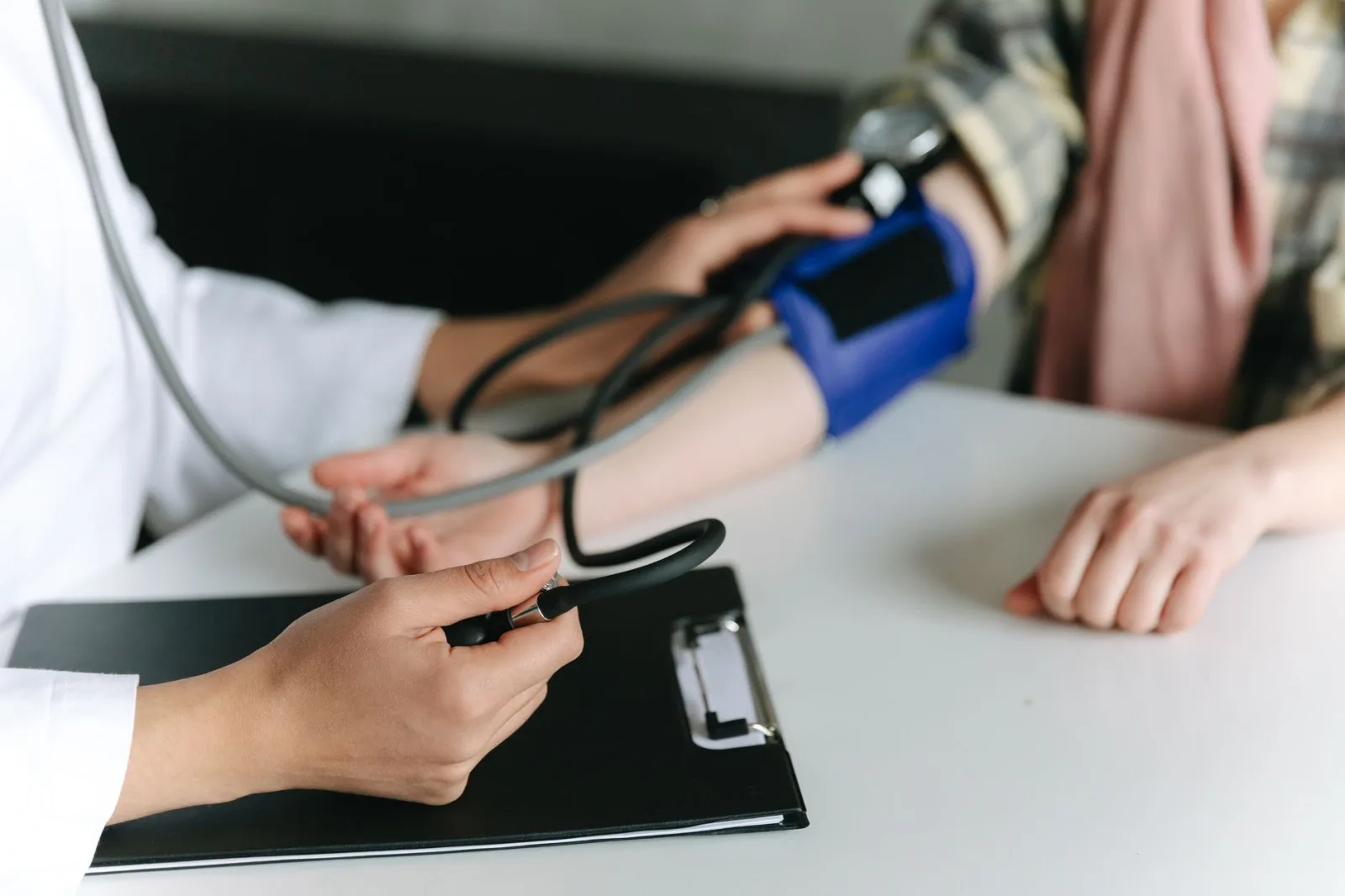 Primer plano de un profesional médico midiendo la presión arterial de un paciente en una clínica.