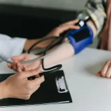 Primer plano de un profesional médico midiendo la presión arterial de un paciente en una clínica.