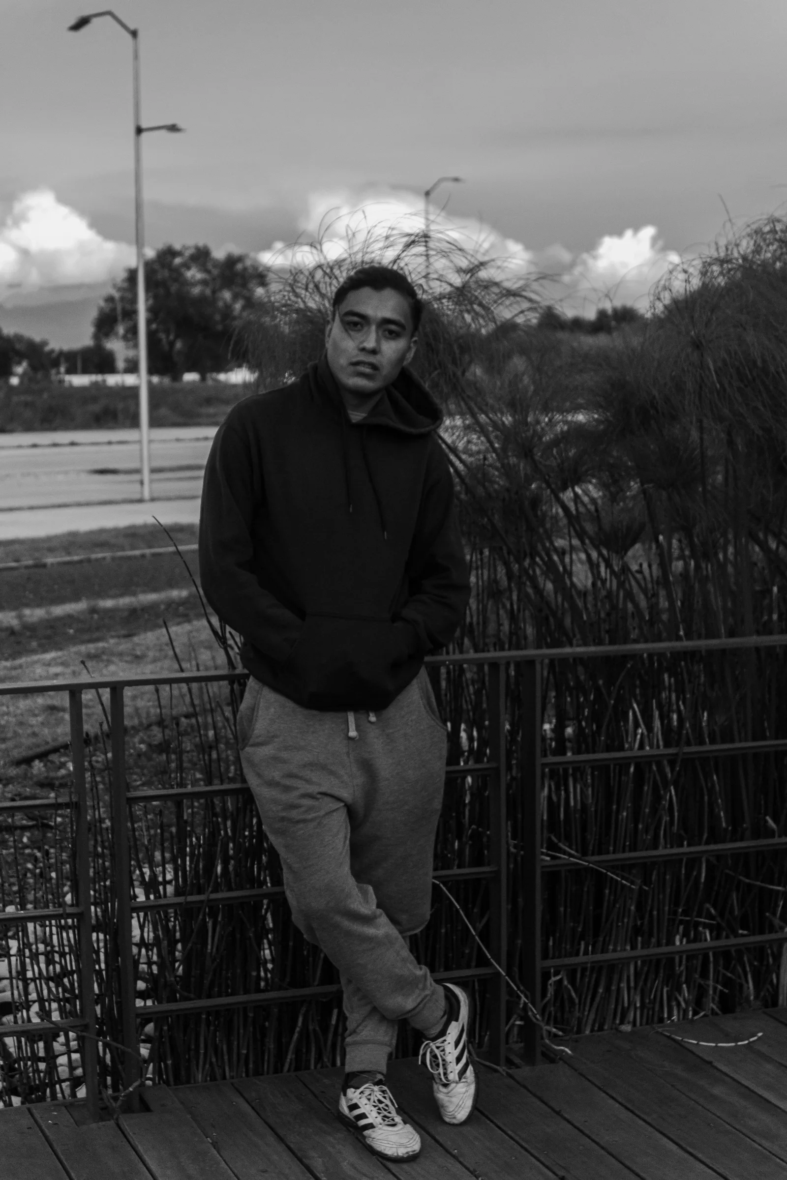 A black and white portrait of a man in a hoodie on a wooden pier in San José Chiapa, Mexico.