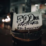 A street pole displaying a protest sign with the message '500 mil motivos p/o impeachment' at night.