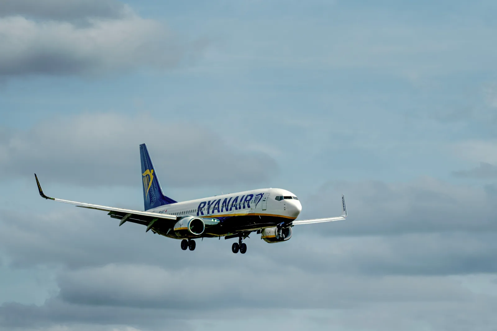 Avión de Ryanair en pleno vuelo con un cielo nublado de fondo, que ilustra los viajes aéreos.