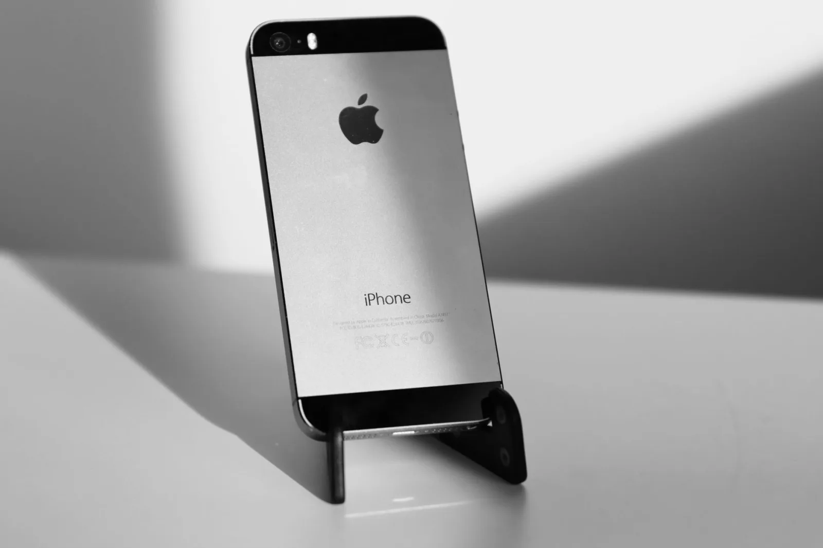 Primer plano elegante en blanco y negro de un iPhone sobre un soporte, que destaca su diseño minimalista.