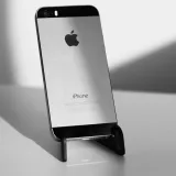 Primer plano elegante en blanco y negro de un iPhone sobre un soporte, que destaca su diseño minimalista.