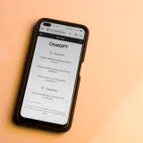 Un smartphone muestra el sitio web de ChatGPT en tonos cálidos, destacando la tecnología de inteligencia artificial.