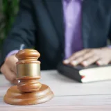 Un mazo de madera y un libro de leyes representan la justicia en un entorno judicial, destacando el orden y la autoridad legal.