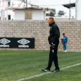 A soccer coach attentively observes a training session, standing by the sideline.