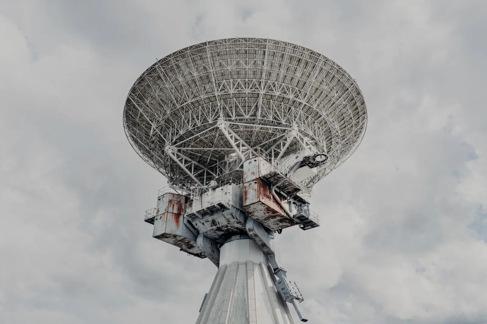 Primer plano de un gran radiotelescopio bajo un cielo nublado.