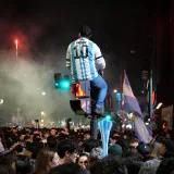 People celebrating in Buenos Aires, Argentina at night, featuring a person in a sports jersey over a crowd.