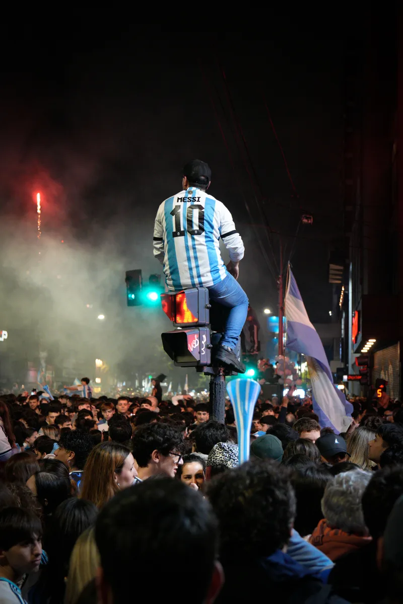 People celebrating in Buenos Aires, Argentina at night, featuring a person in a sports jersey over a crowd.