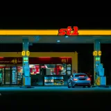 A car refuels at the illuminated St1 gas station in Jönköping, Sweden at night.