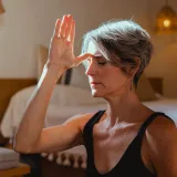 Serene elderly woman practicing yoga meditation indoors, symbolizing wellness and positive aging.