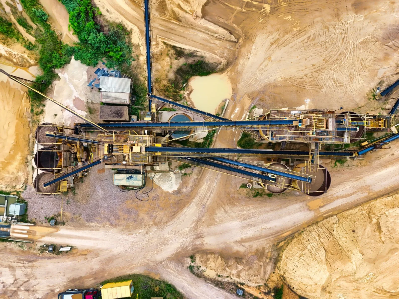 Vista aérea de una extensa explotación minera industrial con maquinaria pesada y terreno detallado.