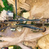 Vista aérea de una extensa explotación minera industrial con maquinaria pesada y terreno detallado.