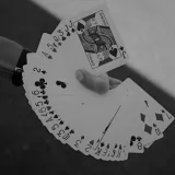 Artistic black and white photo of a hand displaying a fan of playing cards outdoors.